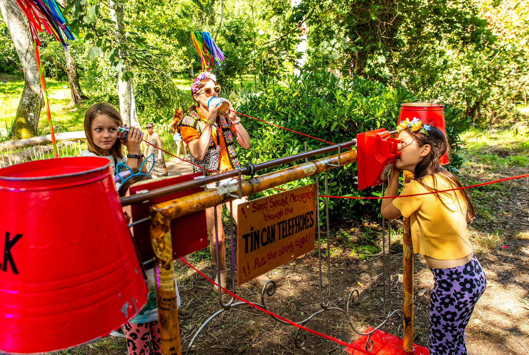three people using tin cans attached to string to talk to each other through 'tin-can-telephones'