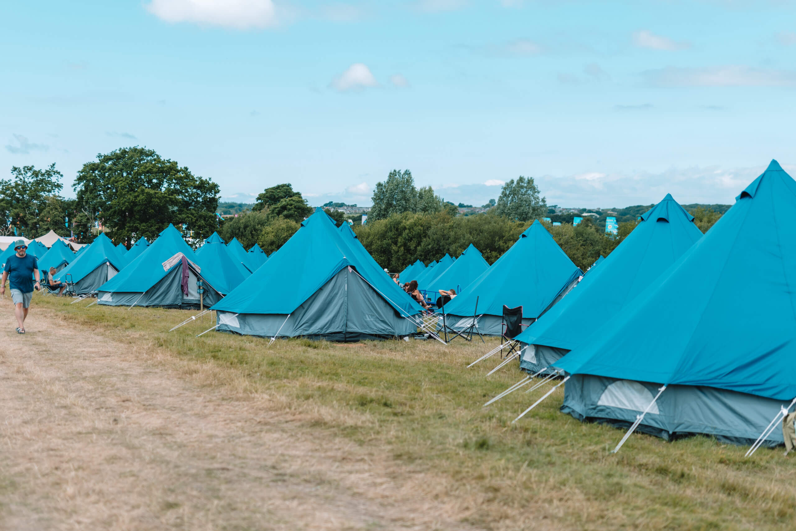 A row of blue pitched bell tents in a field