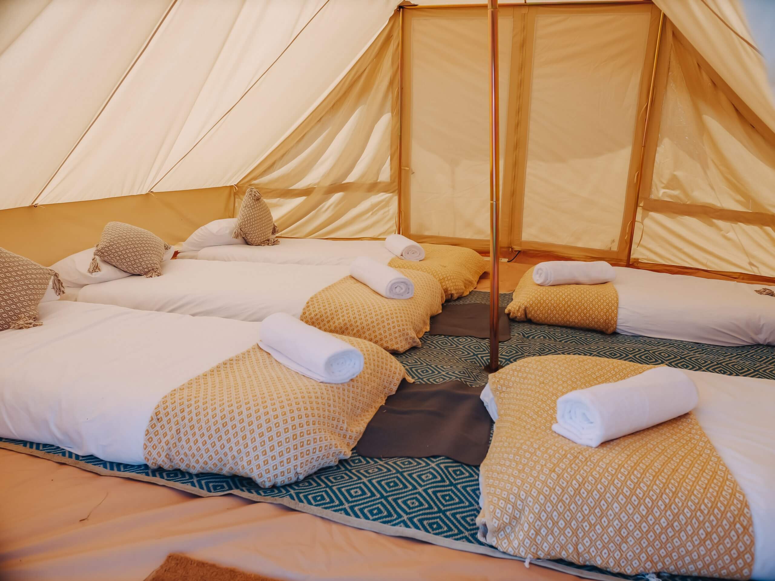 5 single mattress with bedding on the floor of a bell tent