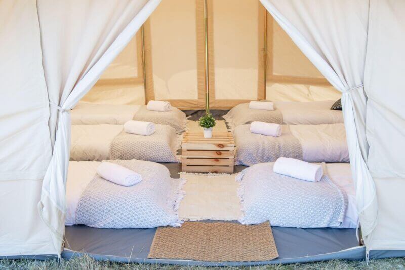 opening of a bell touareg looking at 6 single mattresses 3 on each side with bedding and a wooden box table