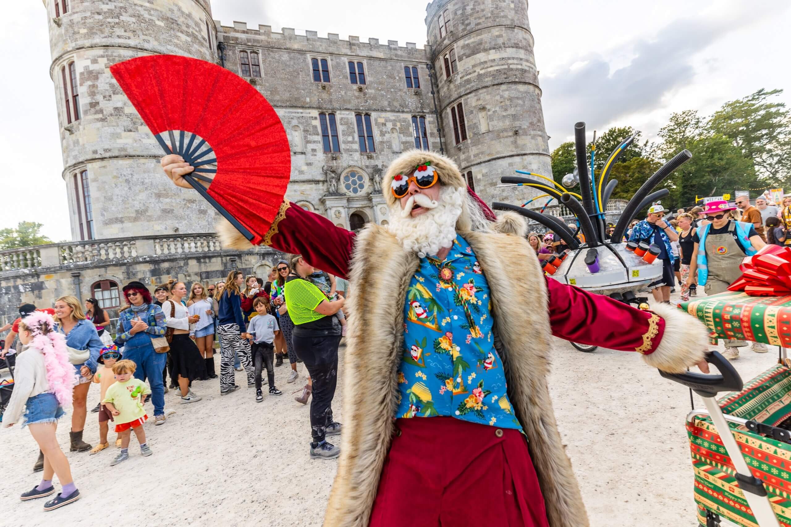 Father Christmas holding a fan in front of Lulworth Castle
